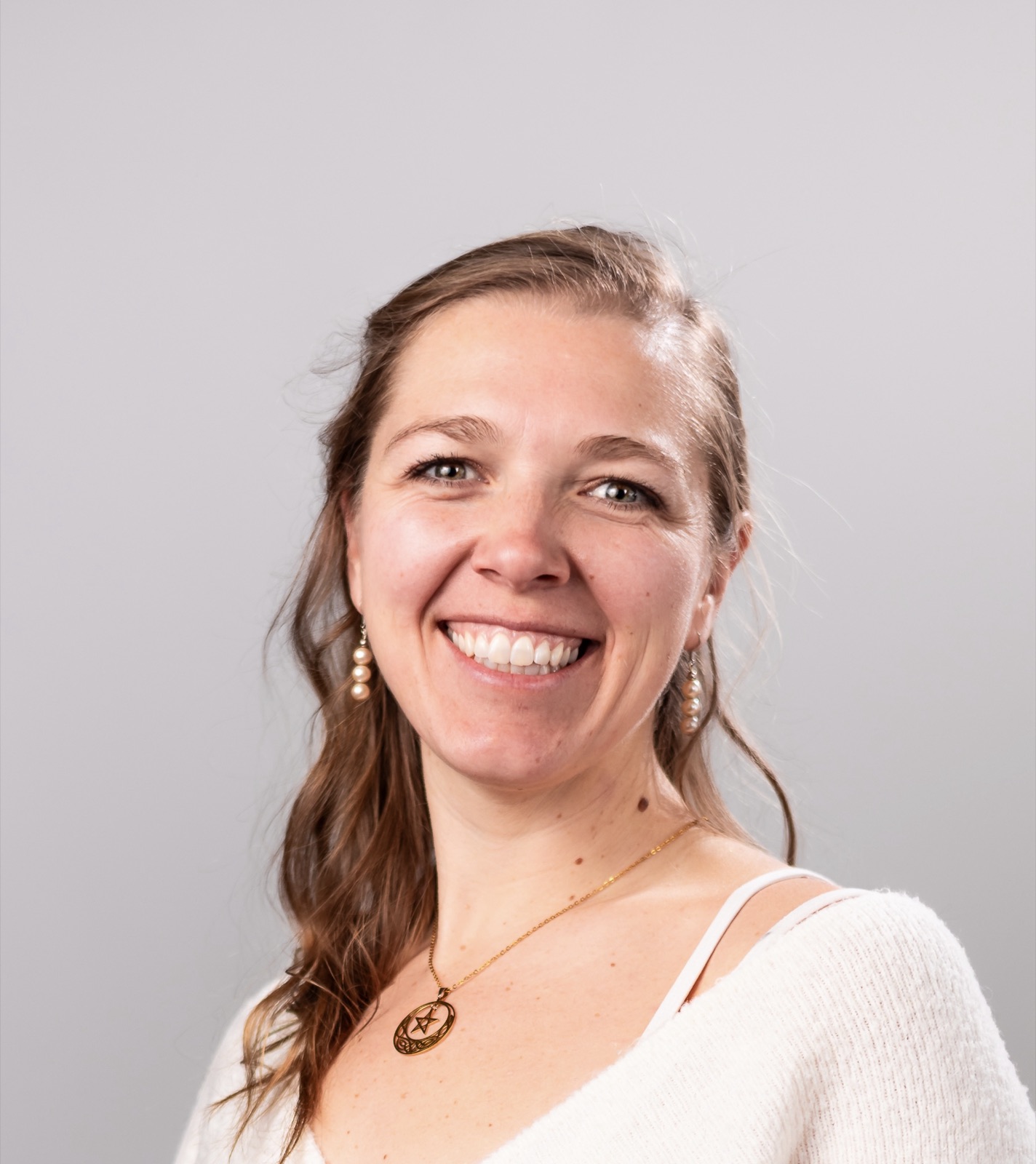 Close-up headshot of Amber Campbell smiling against a soft grey studio background